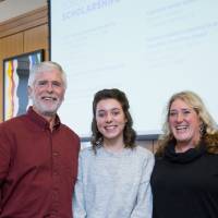 A student standing with two donors.